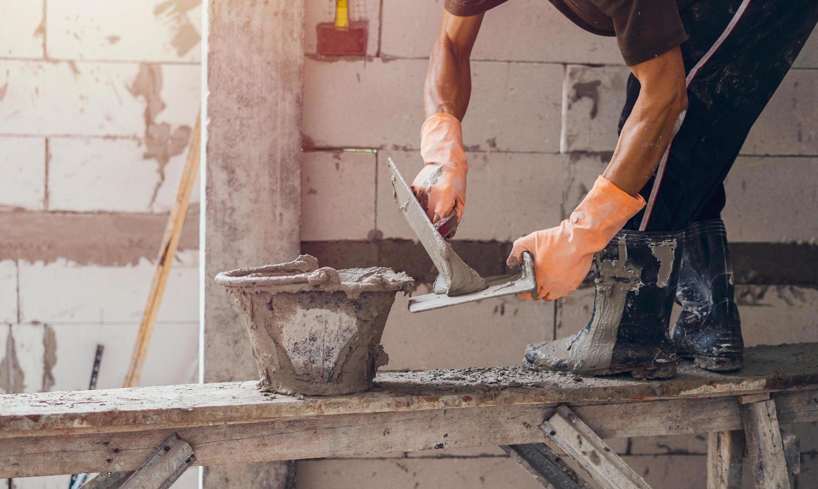 Nahaufnahme eines Arbeiters, der eine Zementwand für den Hausbau verputzt foto