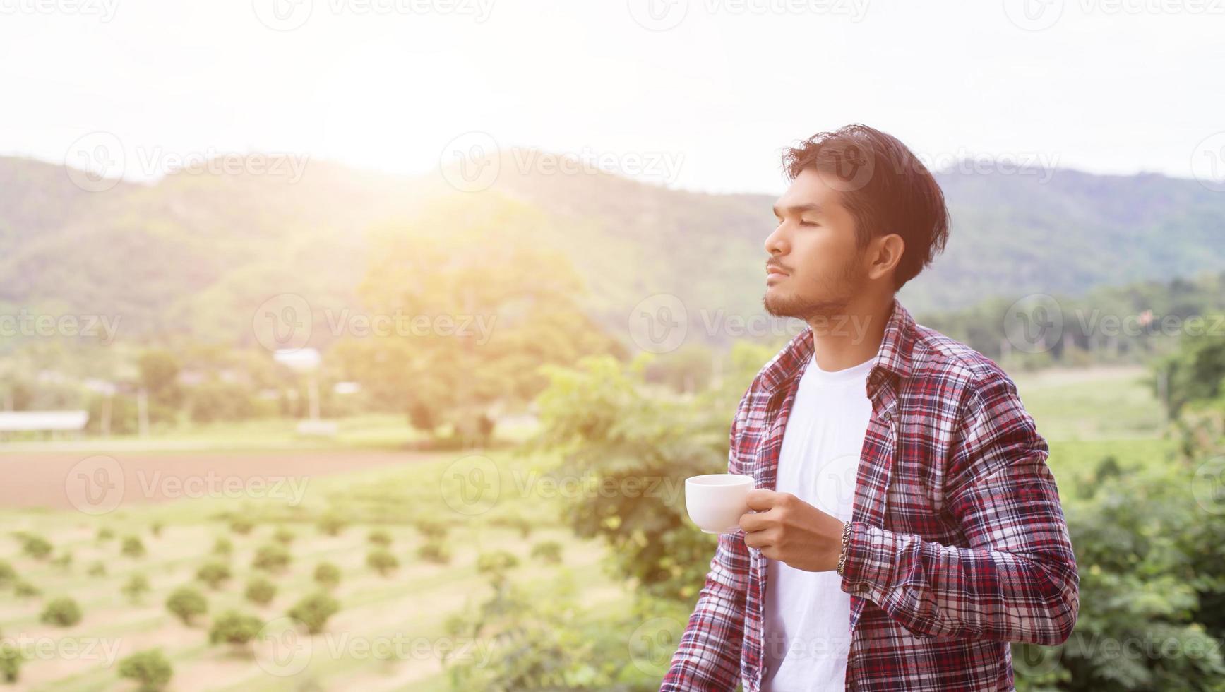 hübscher bärtiger Hipster-Mann mit einer Tasse Kaffee am Morgen, der im Park spazieren geht. foto