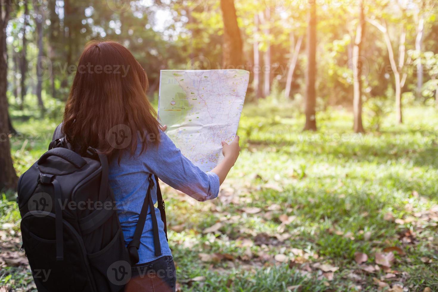 Frauenwanderer mit Rucksack prüft Karte, um Wegbeschreibungen im Wildnisgebiet zu finden foto