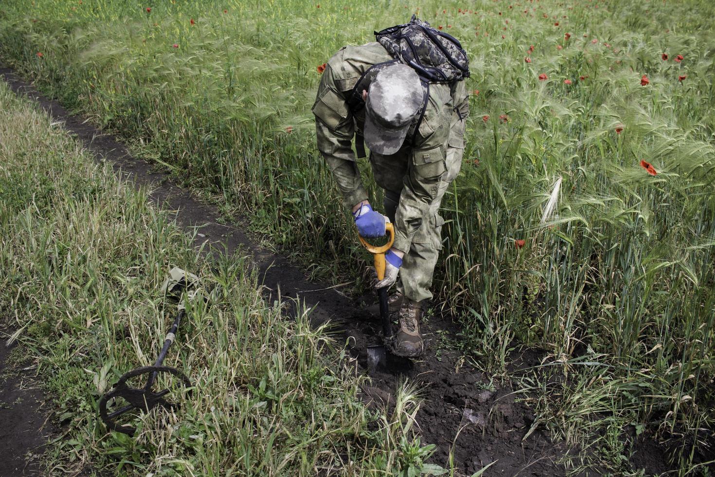 Soldat mit einem Metalldetektor in Feldern foto