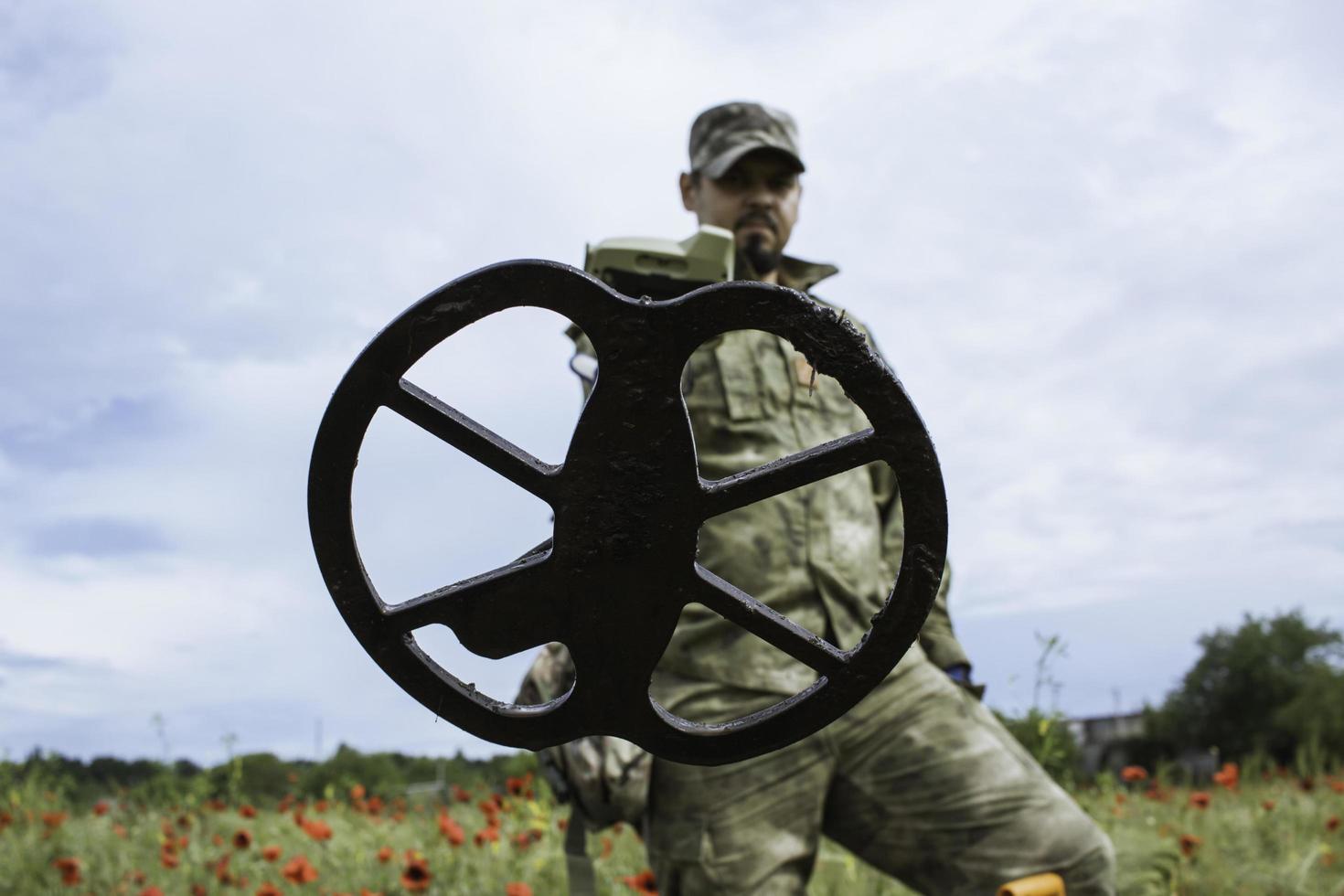 Soldat mit einem Metalldetektor in Feldern foto