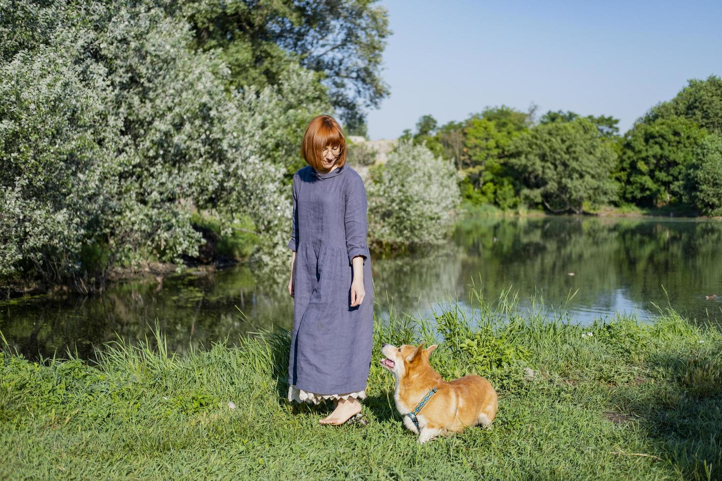 Junge Frau im Retro-Kleid mit lustigem Corgi-Hund auf dem Picknick foto