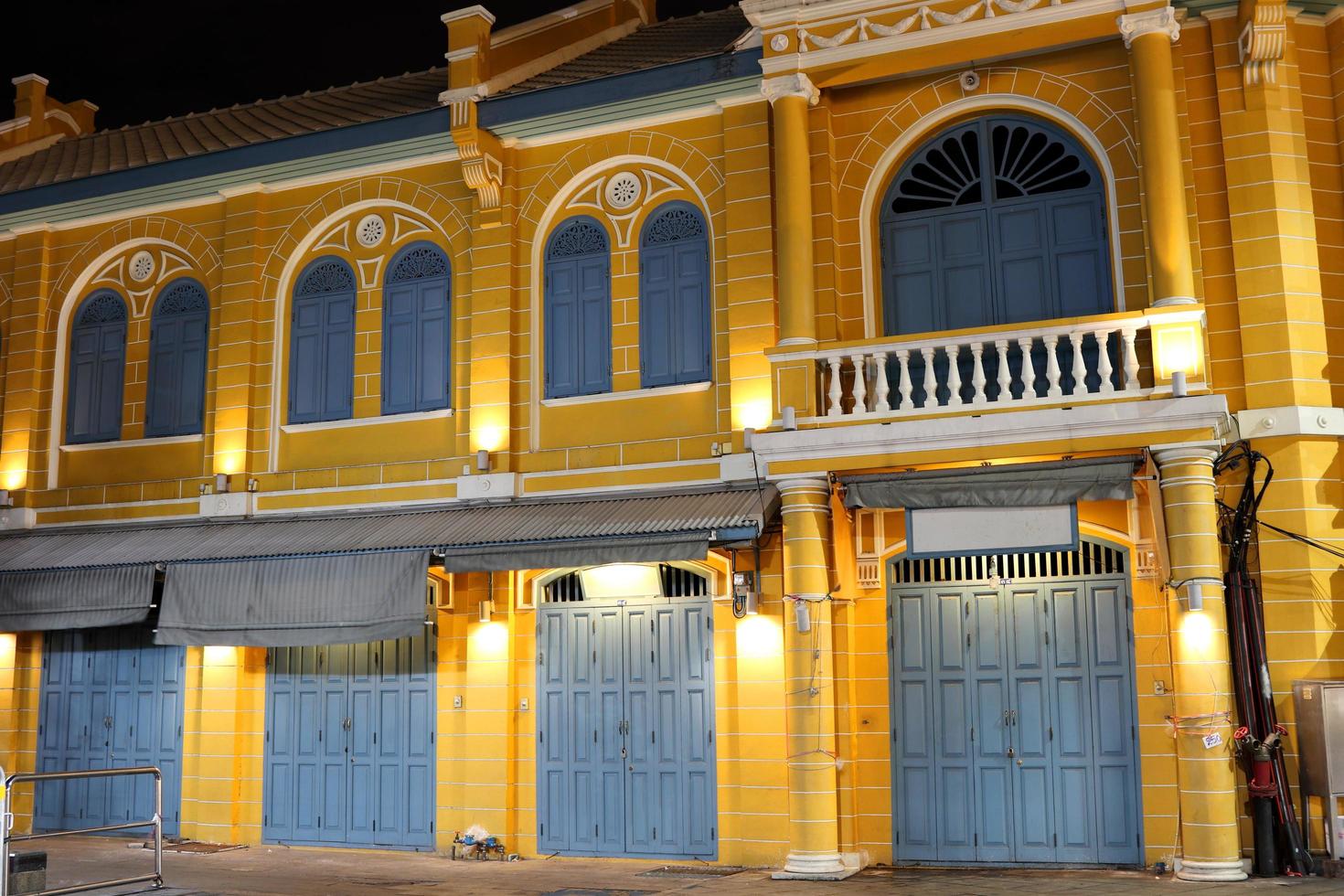 Gelbes Retro-Gebäude, blaugraue Tür und Fenster in Bangkok bei Nacht, Gebäude im europäischen Stil. foto