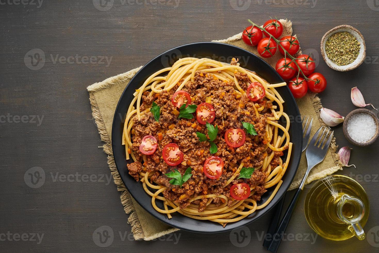 Pasta Bolognese Bucatini mit Hackfleisch und Tomaten, dunkler Holzhintergrund, Draufsicht, Kopierraum foto