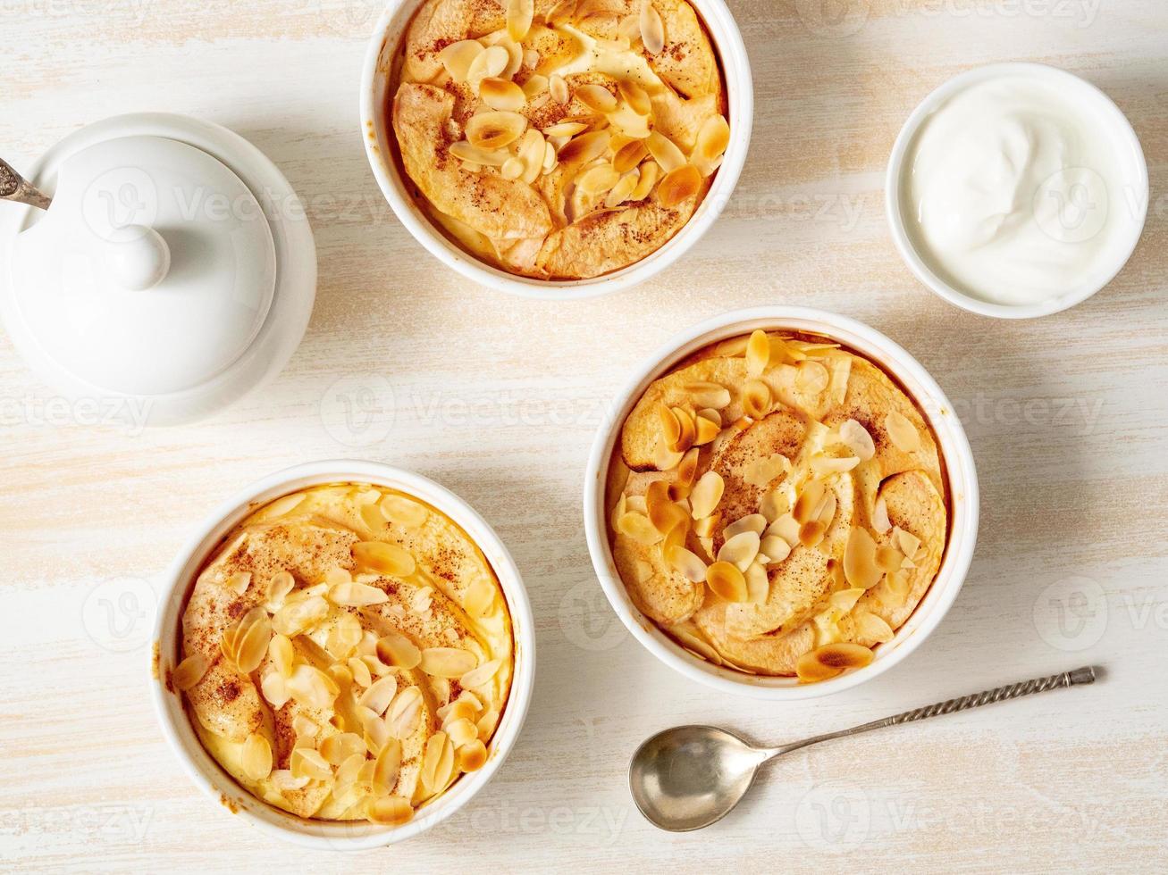 Käsekuchen auf weißem Holztisch in der Küche. feines Quarkdessert mit Äpfeln, Mandelblättchen foto