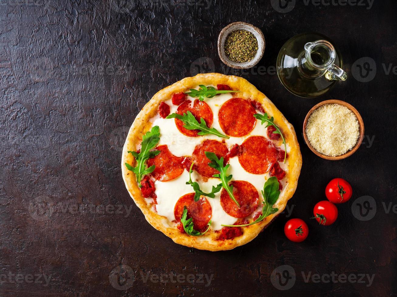 Heiße hausgemachte italienische Peperoni-Pizza mit Salami, Mozzarella auf einem dunkelbraunen Steintisch, Draufsicht, Kopierraum foto