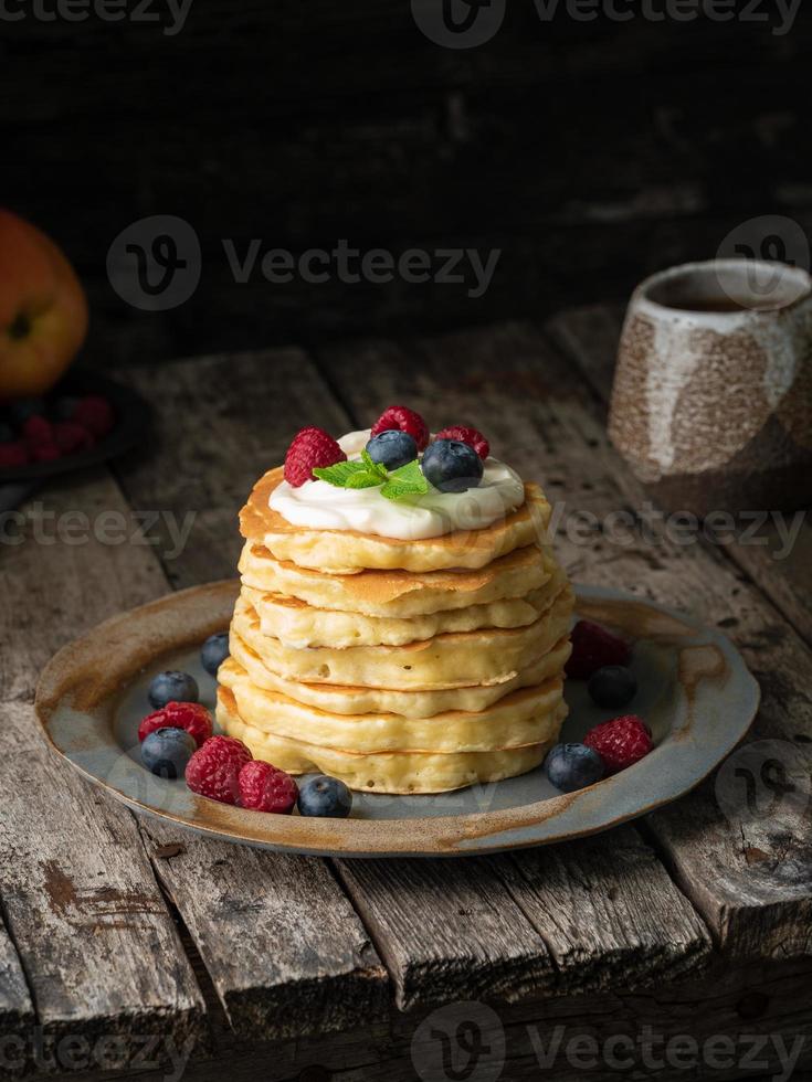 Pfannkuchen mit Vanillecreme, Heidelbeeren und Himbeeren. Seitenansicht, vertikal. foto