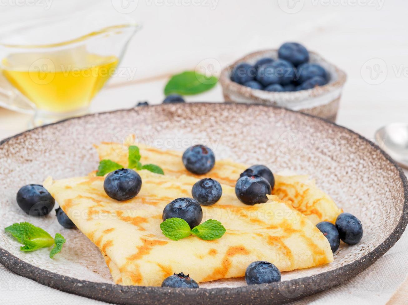 Zwei Pfannkuchen mit Heidelbeeren und Minze auf Teller, Seitenansicht, Makro, Nahaufnahme foto