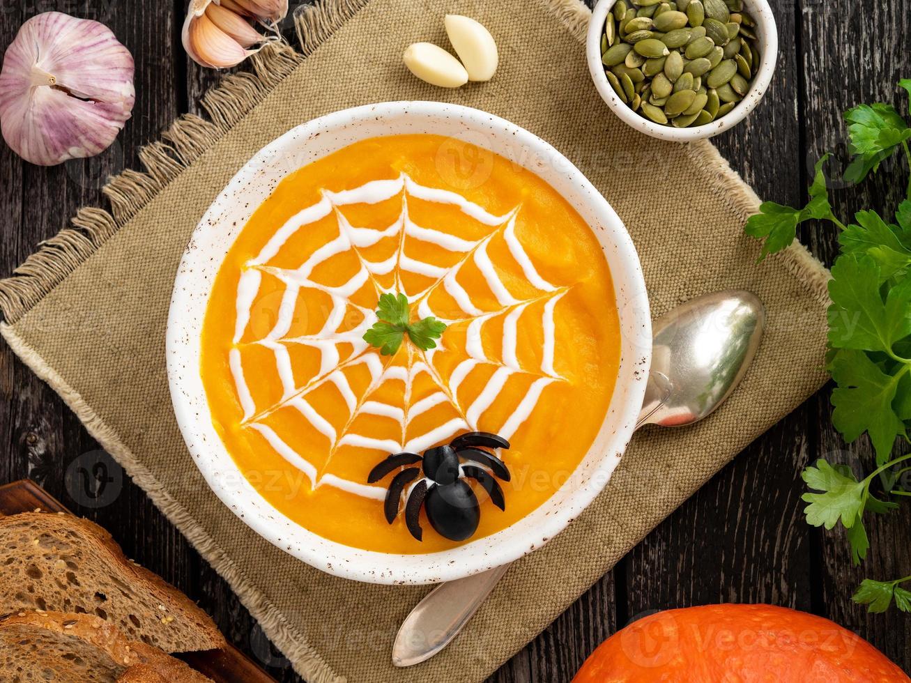 lustiges essen für halloween. Kürbispüreesuppe, Spinnennetz, dunkler alter Holztisch, Draufsicht. foto