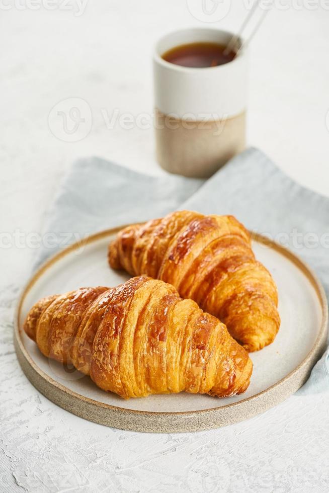 zwei leckere croissants auf teller und heißes getränk im becher. morgens französisches frühstück foto