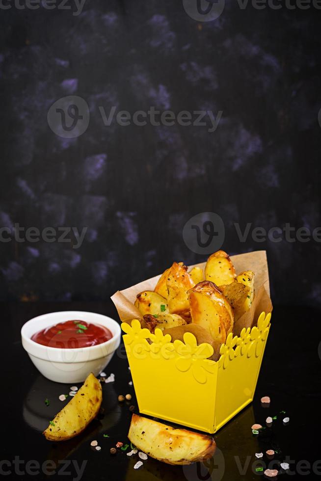 Ofenkartoffel mit Soße und Gewürzen auf dunklem Hintergrund foto