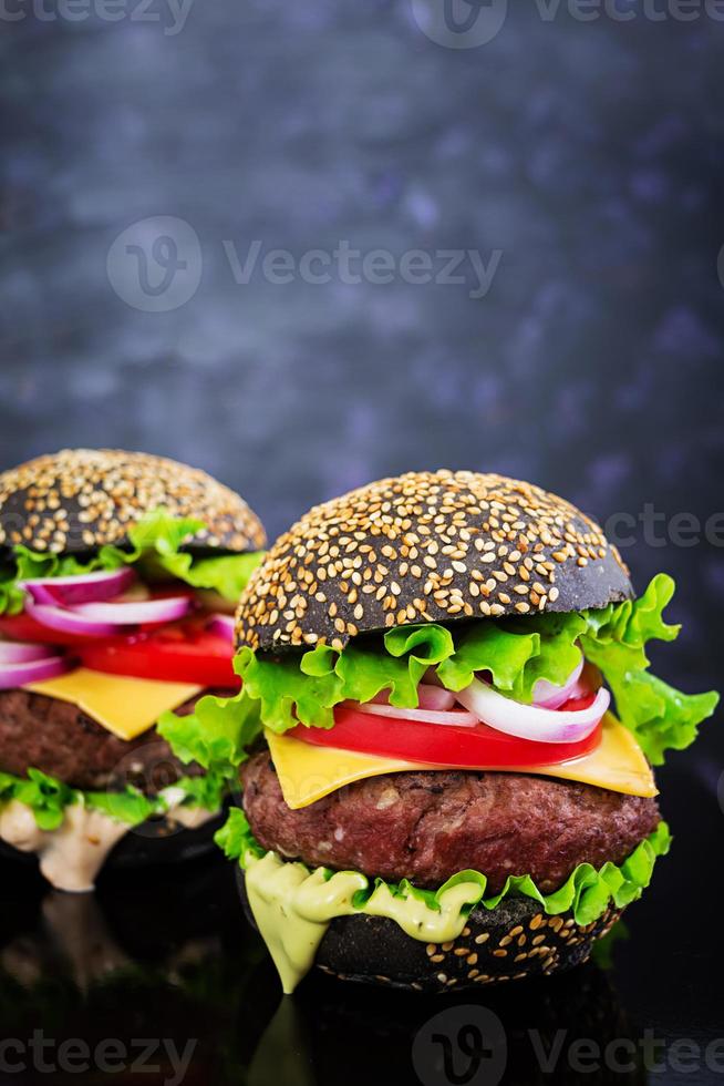 handgemachter Burger auf dunklem Hintergrund. leckerer schwarzer burger foto