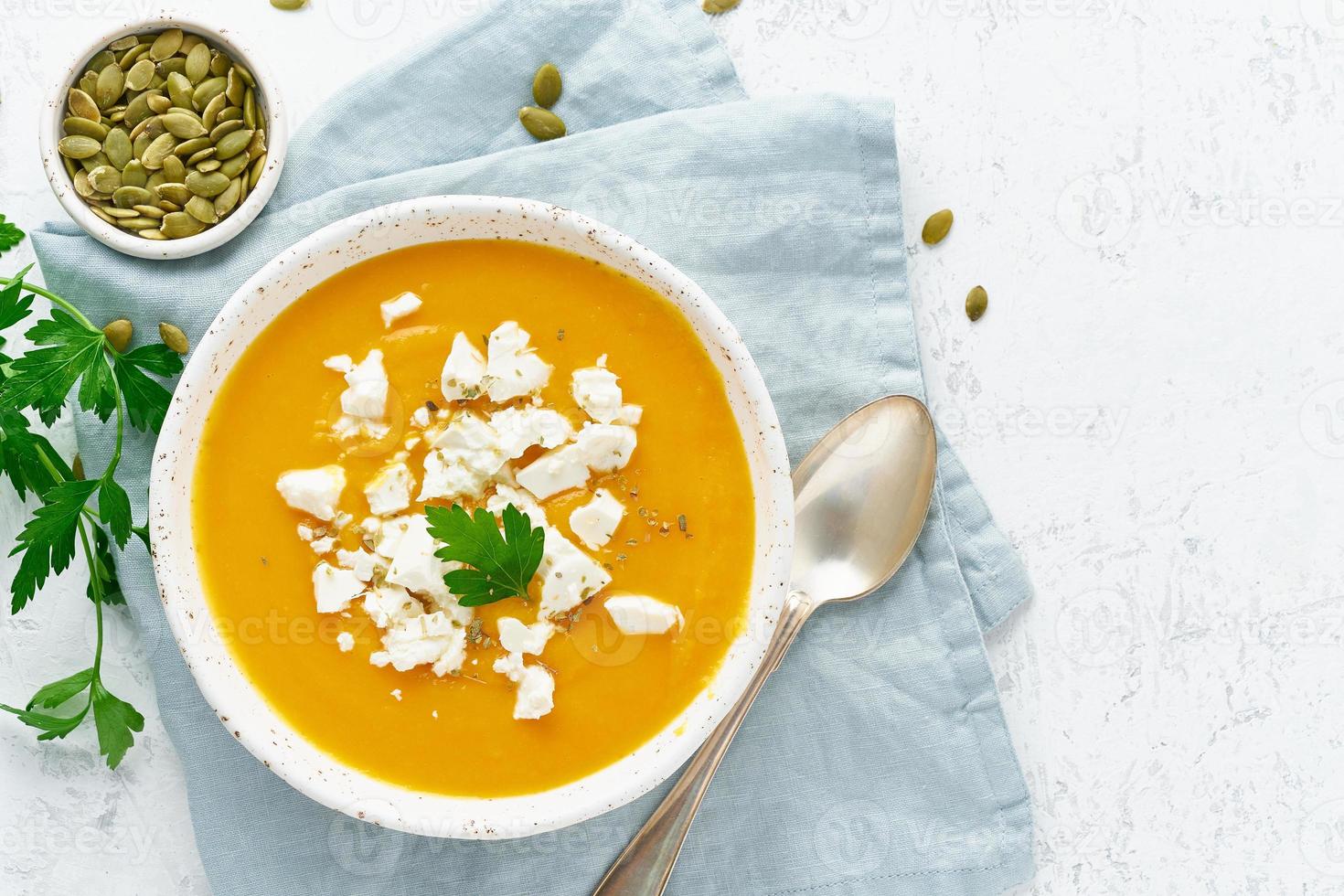 Kürbiscremesuppe mit Schafskäse, hausgemachtes Essen im Herbst, weißer Hintergrund, Draufsicht, Kopierraum foto