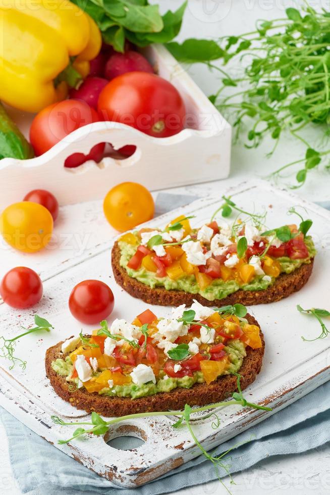 Avocado-Toast mit Feta und Tomaten, Smorrebrod mit Ricotta, Nahaufnahme und vertikal foto