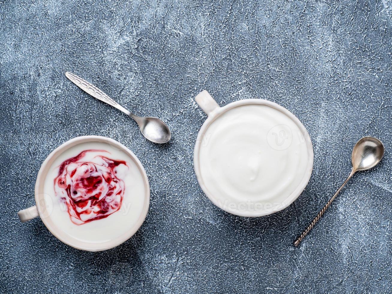 griechischer joghurt mit marmelade in weißer schüssel auf graublauem betonsteintisch, draufsicht, kopierraum foto