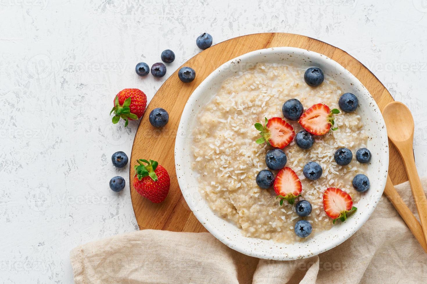 Hafermehlbrei rustikal mit Beeren, Strichdiät, auf Draufsicht des weißen hölzernen Hintergrundes foto