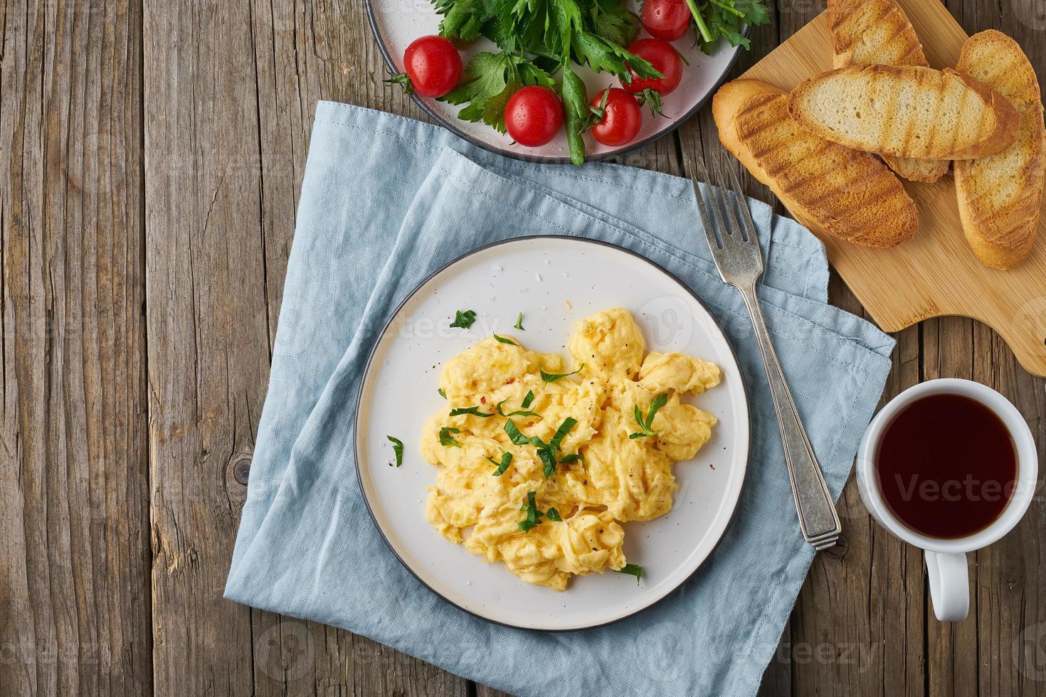 Rührei, Omelett, Draufsicht, Kopierraum. frühstück mit gebratenen eiern, tasse tee, tomaten auf altem holztisch foto