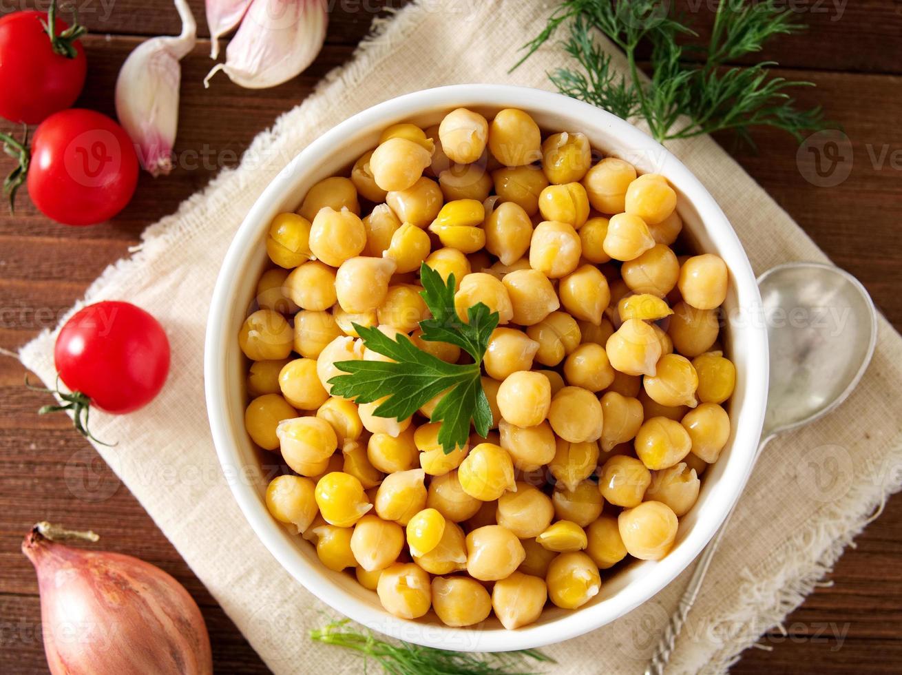 gekochte Kichererbsen auf Schüssel auf dunklem Holztisch. gesund, vegetarisch foto