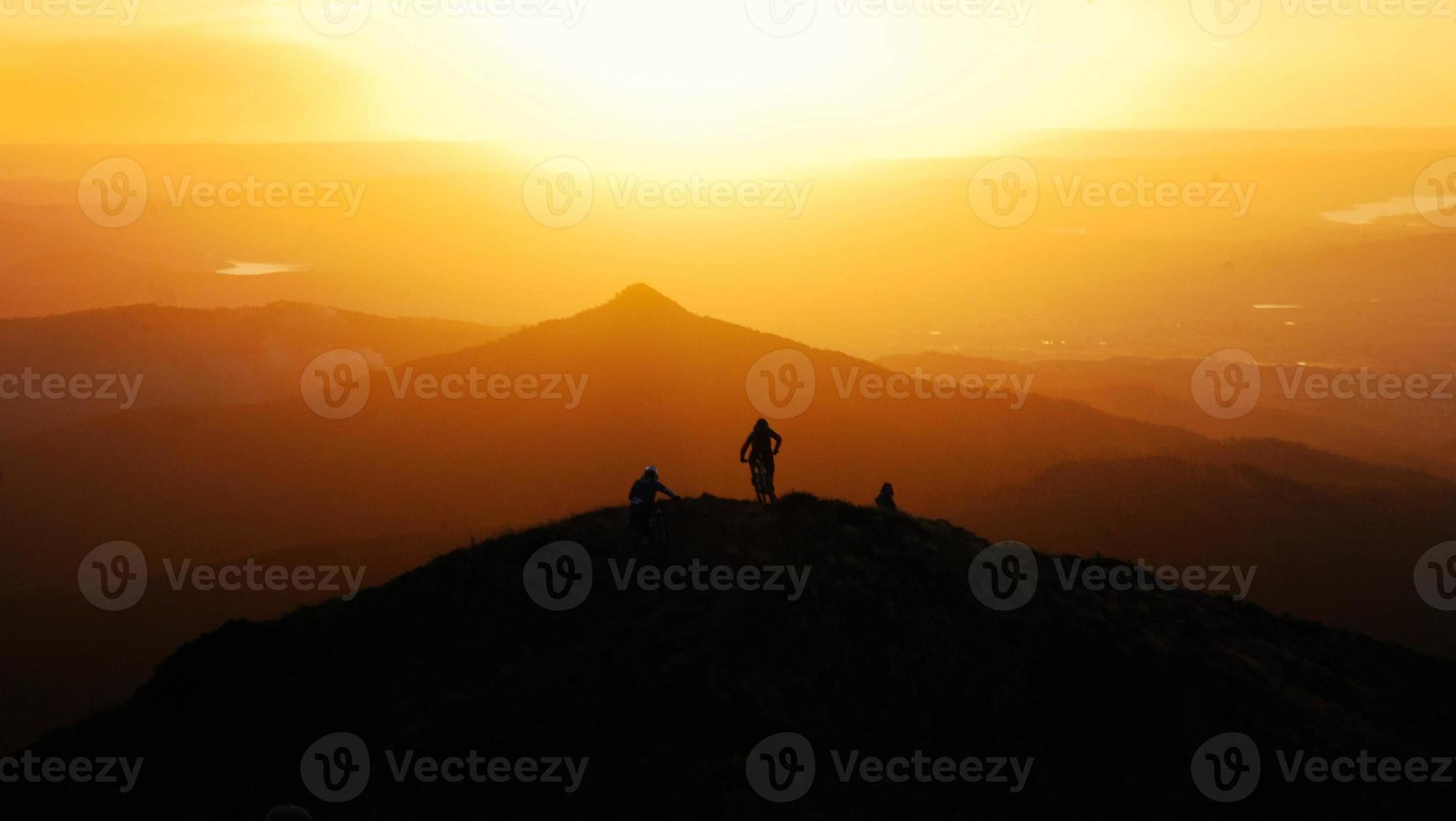 Silhouette des Mountainbikers oben auf Hügel bei Sonnenuntergang foto