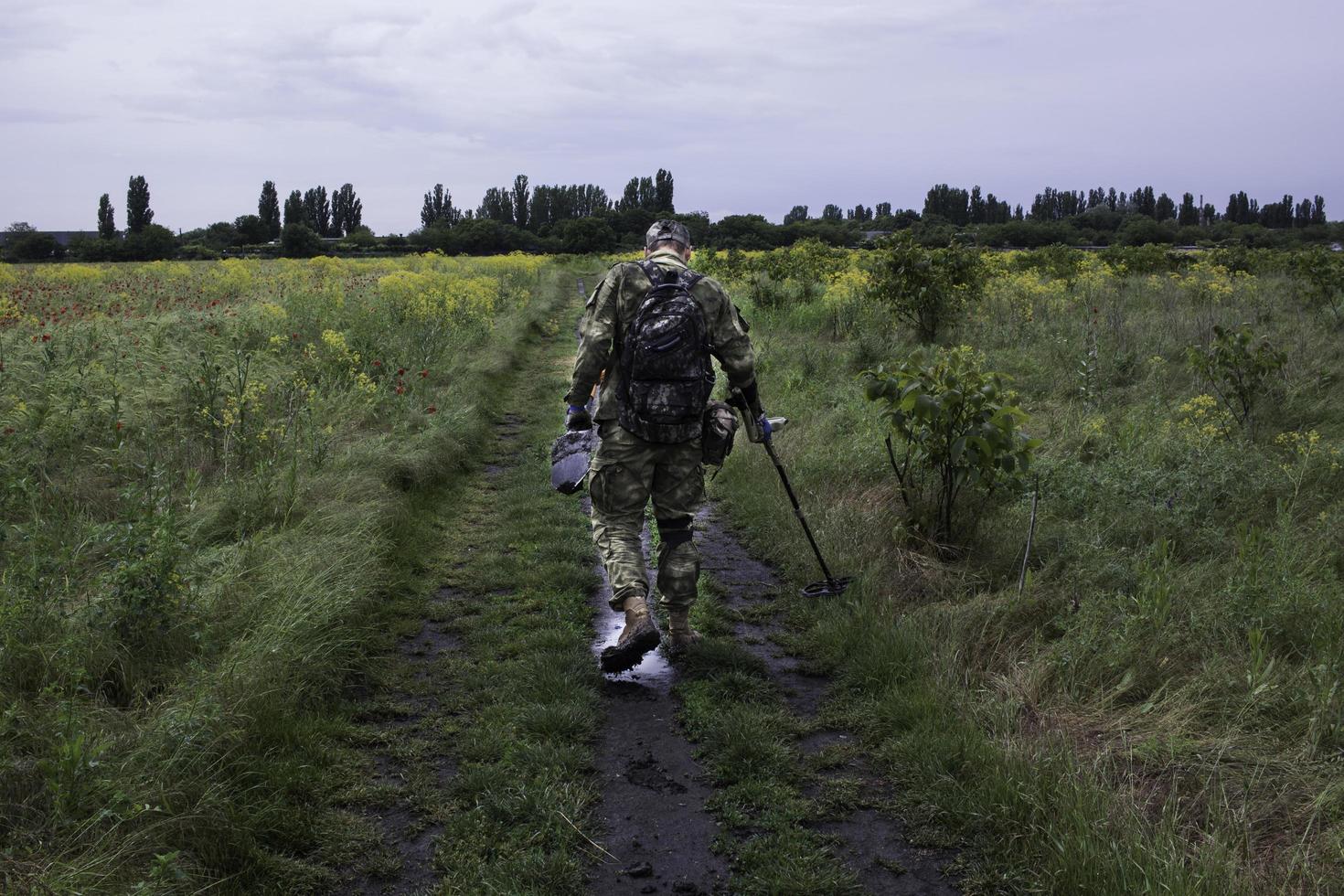Soldat mit einem Metalldetektor in Feldern foto