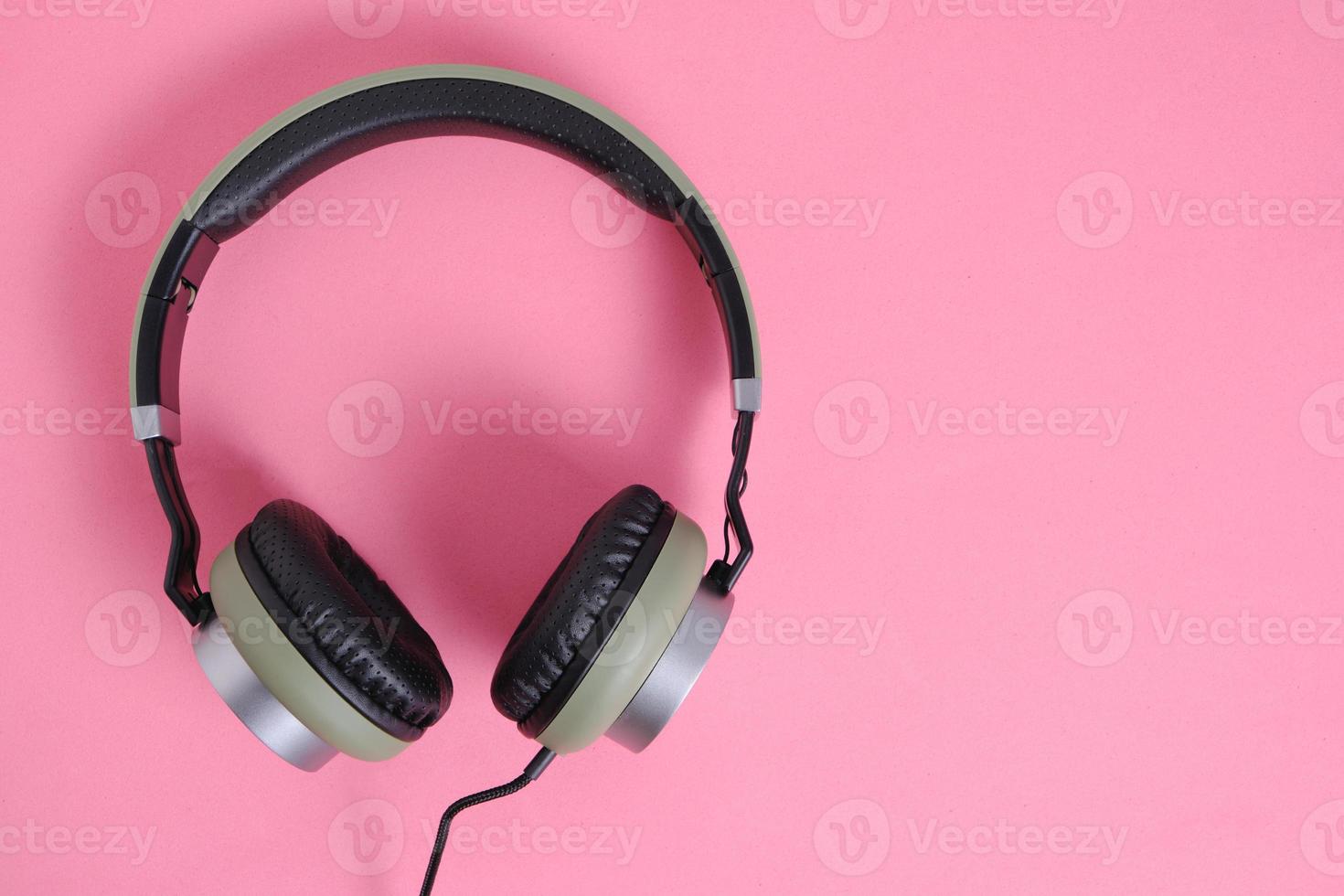 Kabelgebundene Kopfhörer in Khaki auf rosafarbenem Hintergrund. foto