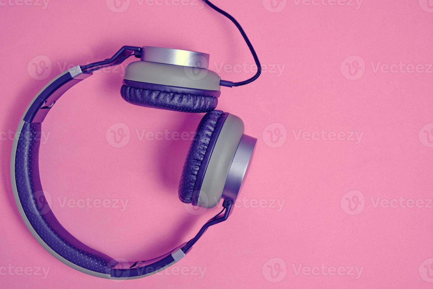 kabelgebundene Kopfhörer in Khaki auf rosafarbenem Hintergrund. Vintage und Retro. foto