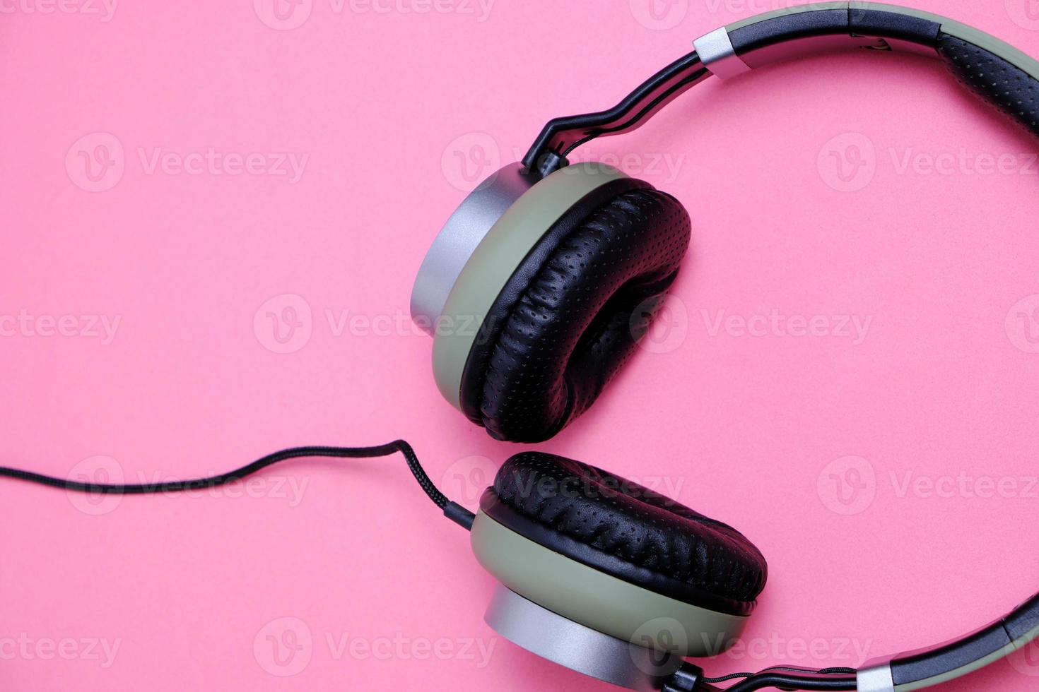 Kabelgebundene Kopfhörer in Khaki auf rosafarbenem Hintergrund. foto