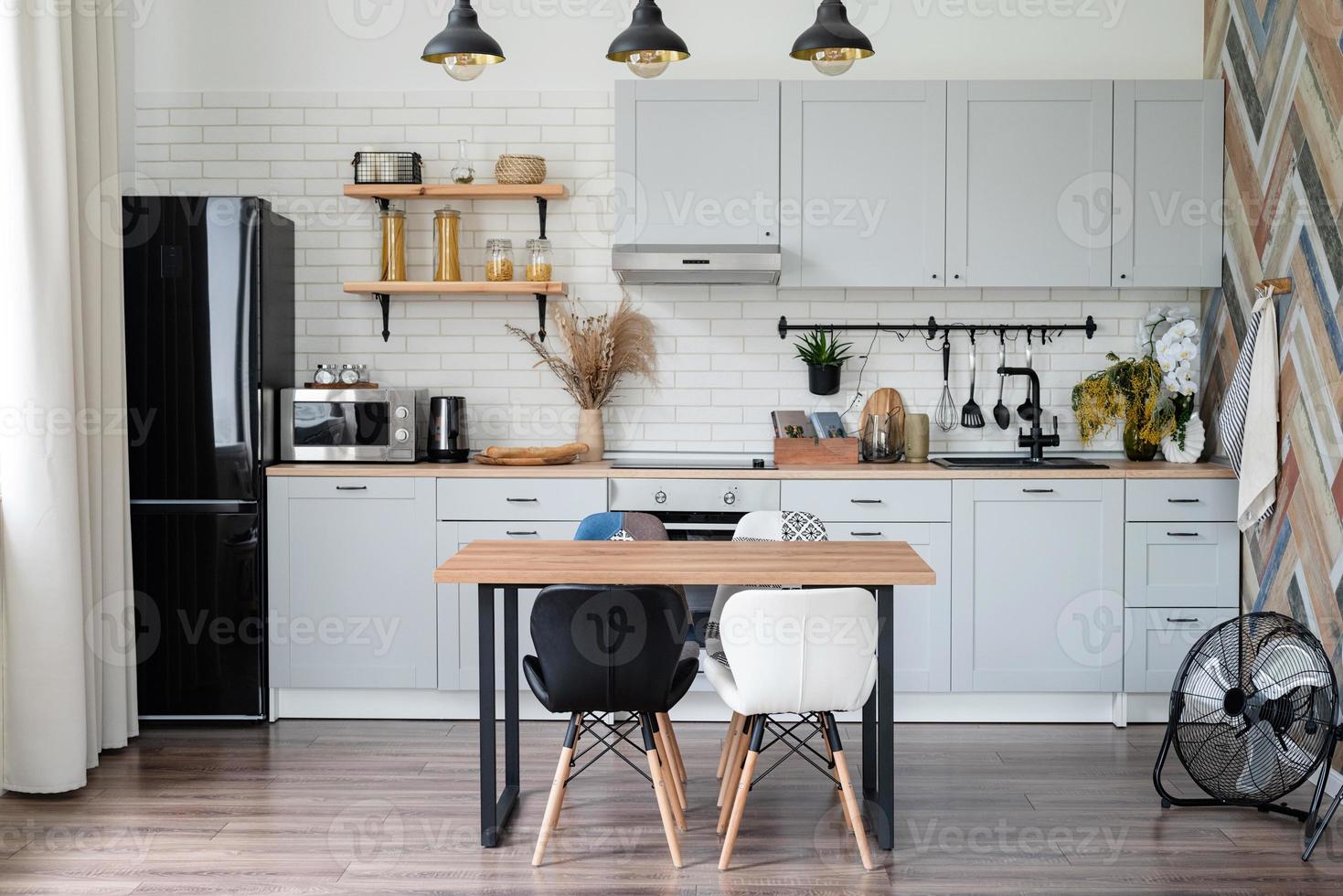 Inneneinrichtung der Küche im rustikalen Stil mit Vintage-Küchengeschirr und Holzwand. Weiße Möbel und Holzdekor in hellem Häuschen im Innenbereich. foto