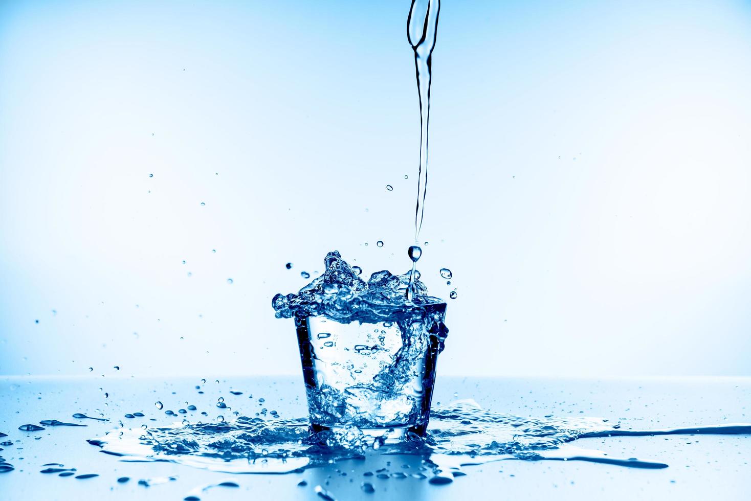 Spritzwasser aus Glas isoliert auf blauem Hintergrund foto