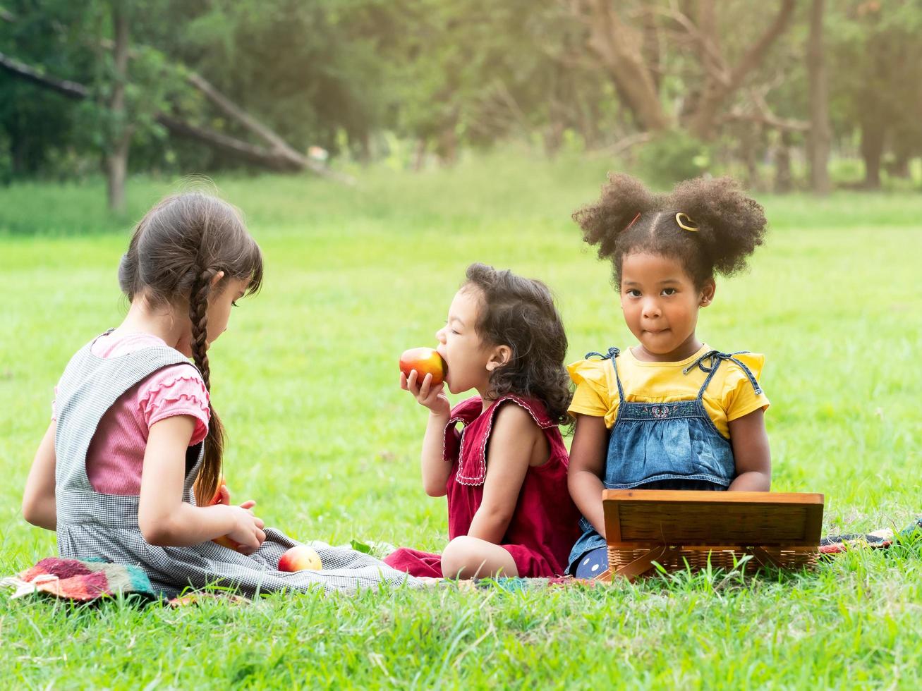 Eine Gruppe kleiner Kinder vieler Nationalitäten spielt und isst Obst außerhalb der Schule foto