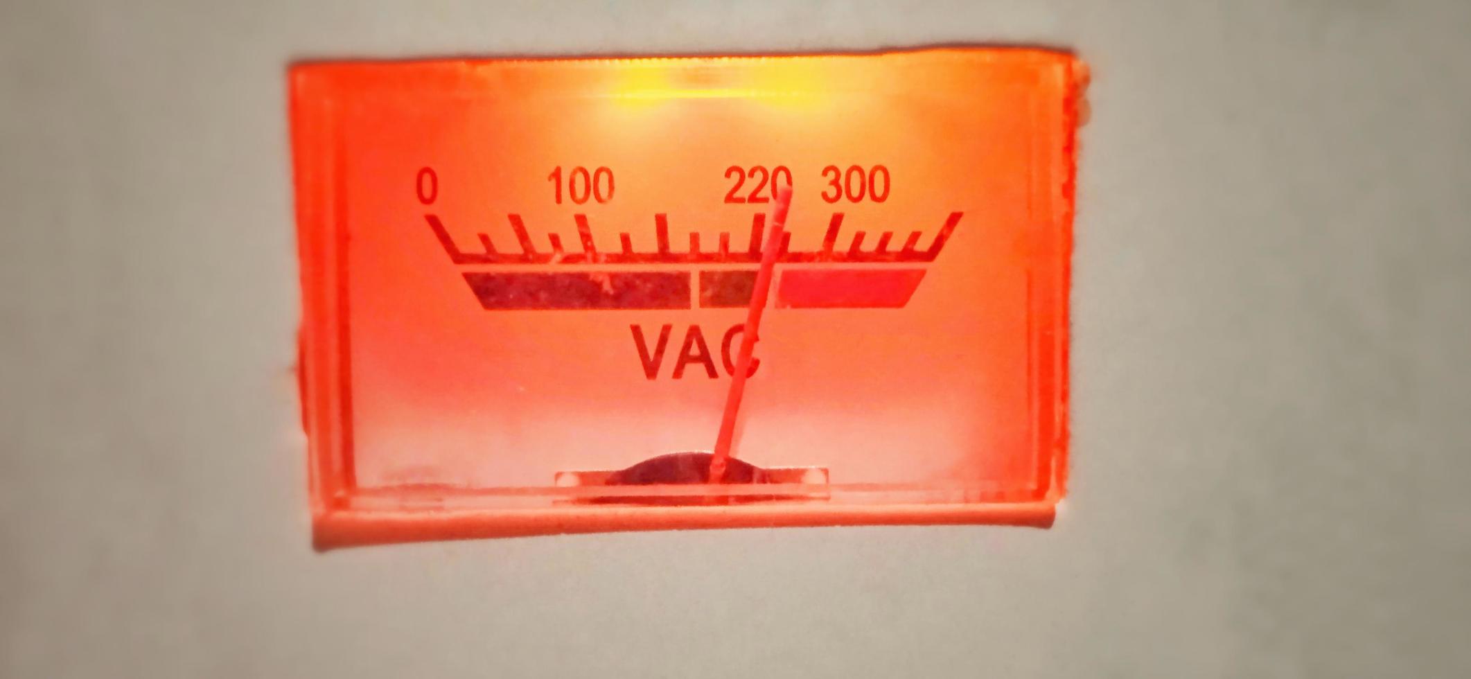 eine isolierte rot-orangefarbene Anzeige der elektrischen Ausrüstung des alten Volt-Ampere-Meters unter schwachem Zustand. foto