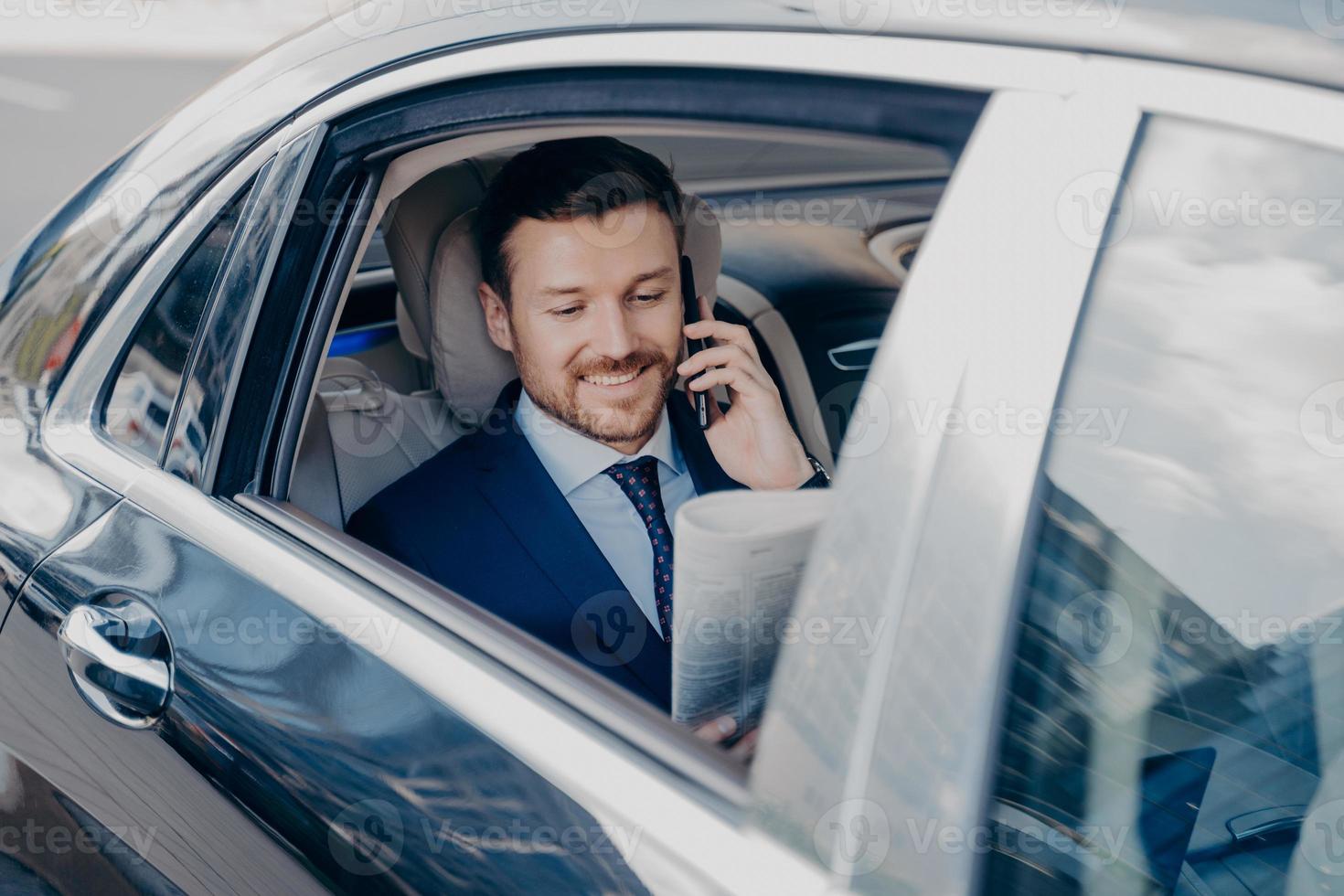 glücklicher junger Geschäftsinhaber, der Zeitung im Auto liest foto