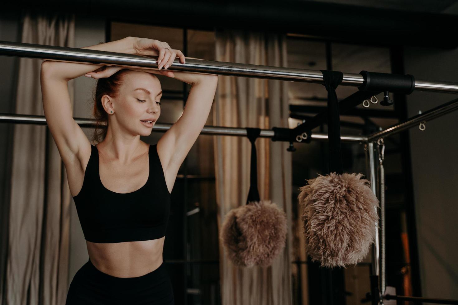 schöne rothaarige fitnessfrau, die sich auf pilates cadillac reformer entspannt foto