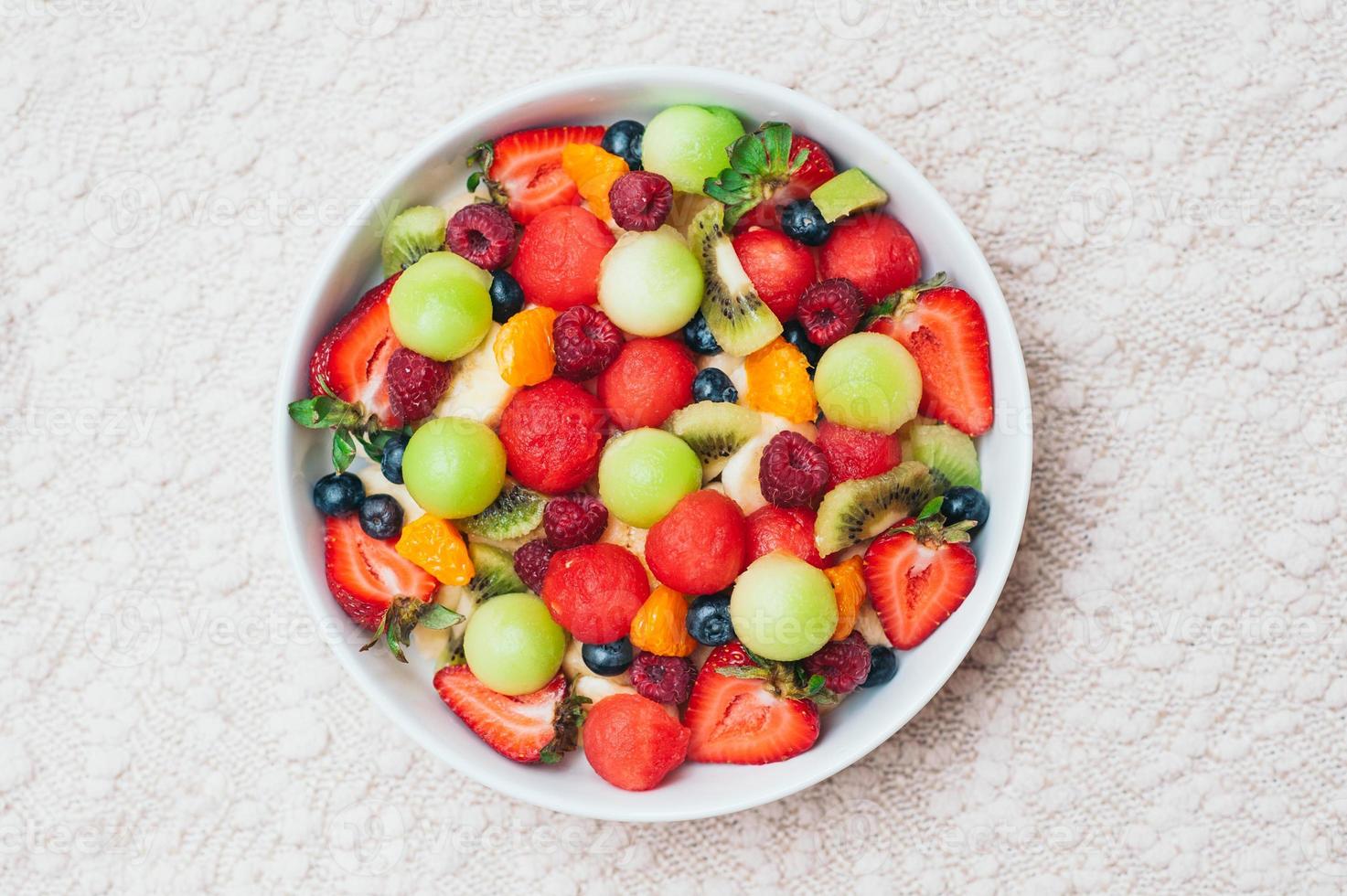 gesunder frischer obstsalat in der schüssel. scheiben von erdbeere, himbeere, kiwi, mandarinen, blaubeere auf teller. leckere Früchte. vegetarisches Gericht. reife Beeren. foto