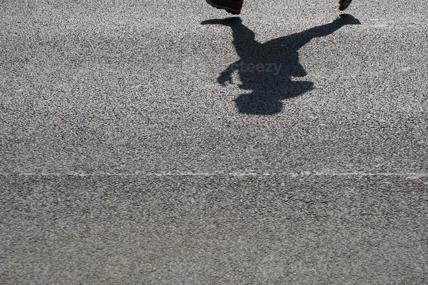Schatten eines nicht erkennbaren Läufers auf Asphalt foto