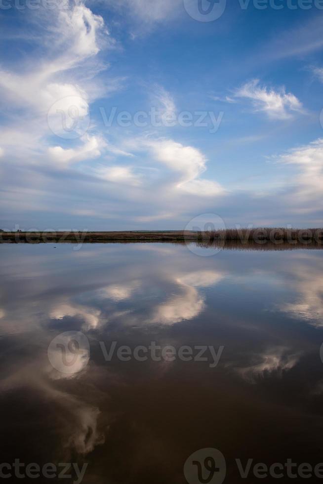bewölkter Himmel reflektiert auf dem Fluss foto