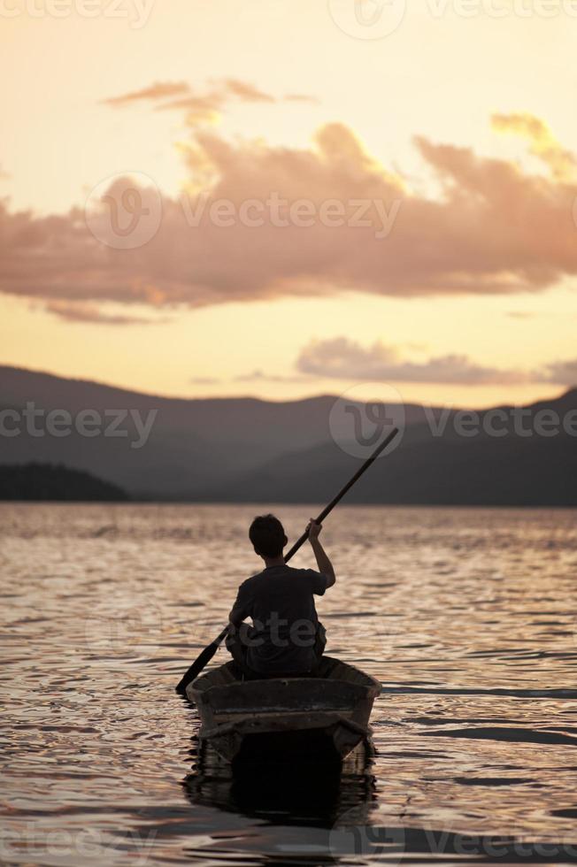 Mann paddelt ein traditionelles Kanu foto