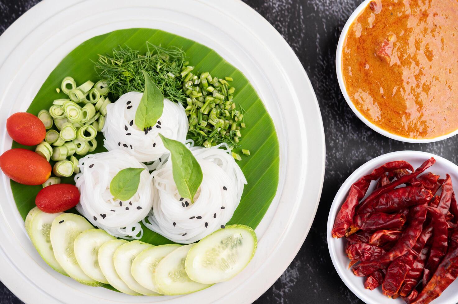 Nudeln im Bananenblatt mit schön angerichtetem Gemüse und Beilagen. Thai Essen. foto