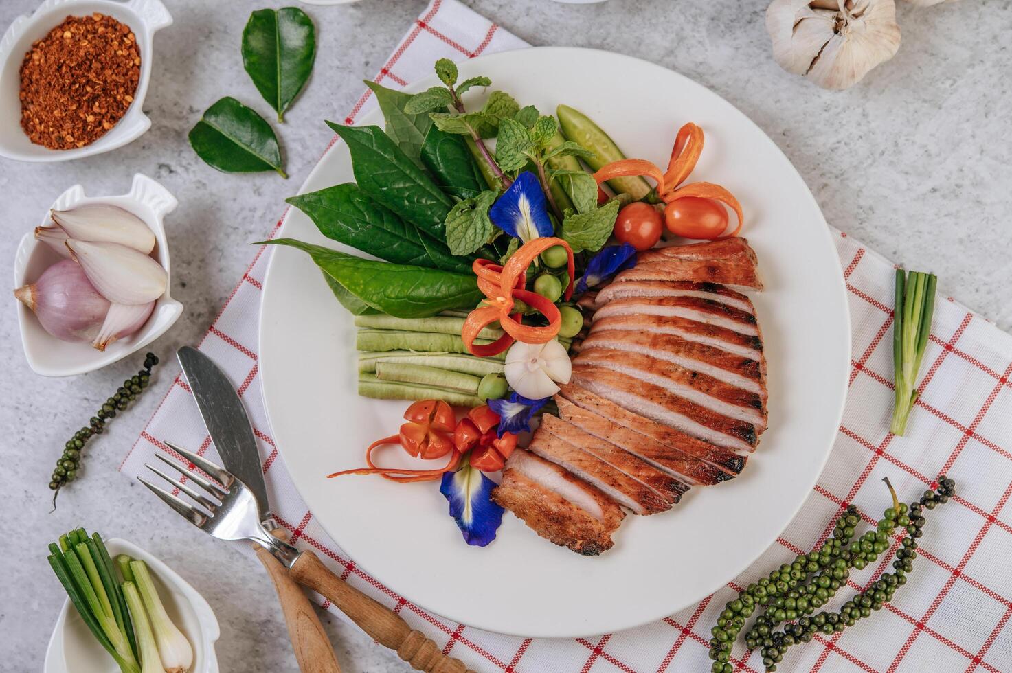 Schweinefleisch mit Zitrone, Zwiebel, roter Zwiebel, Tomate, langer Bohne, Schmetterlingserbsenblüte und Minze. foto