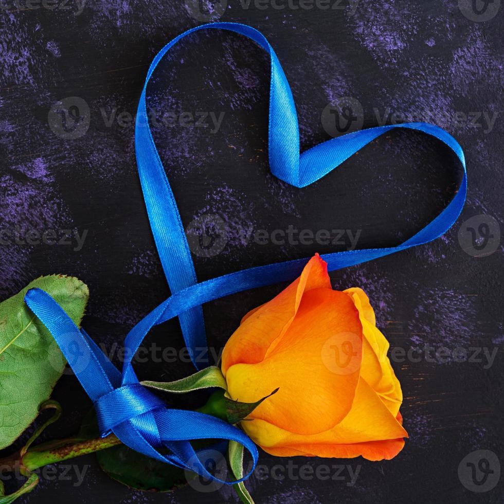 Herzform mit Band und Rosen auf dunklem Hintergrund. Ansicht von oben foto