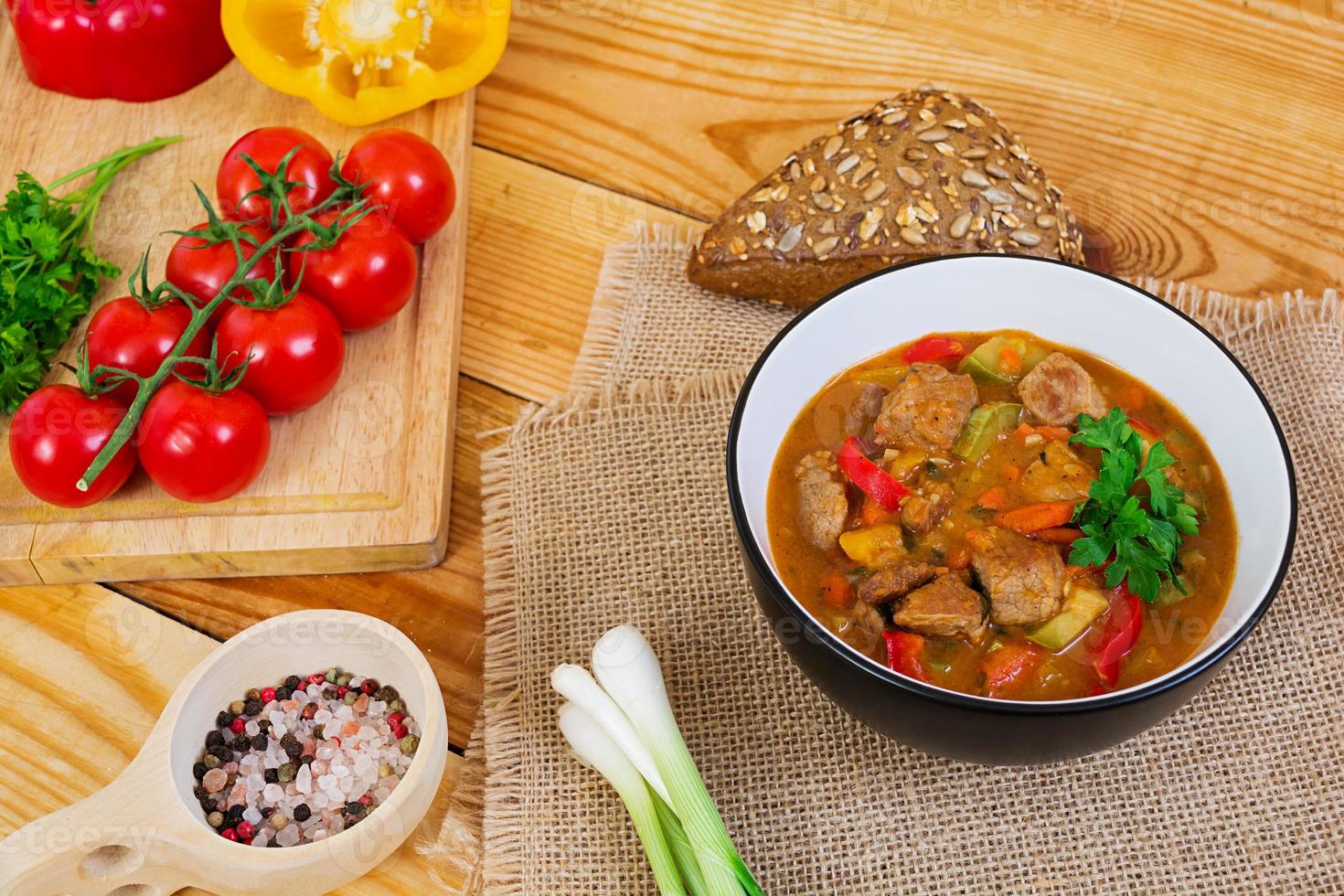 Eintopf mit Fleisch und Gemüse in Tomatensauce auf Holzhintergrund foto