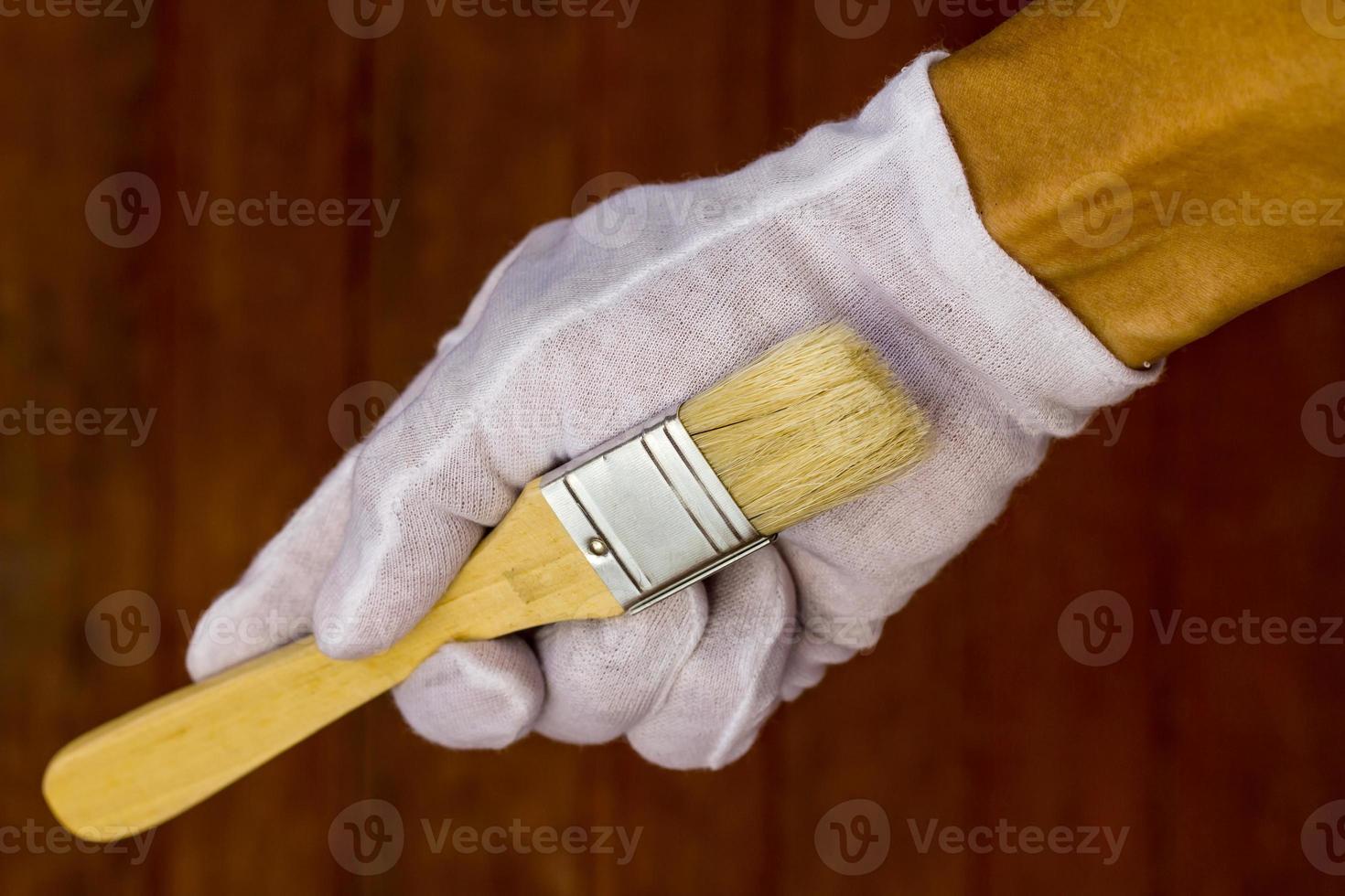 weiße behandschuhte hand, die einen pinsel hält. foto