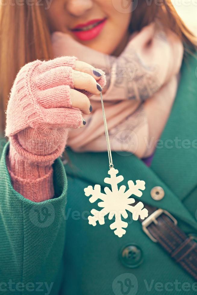 junge Frau, die Schneeflockendekoration hält foto