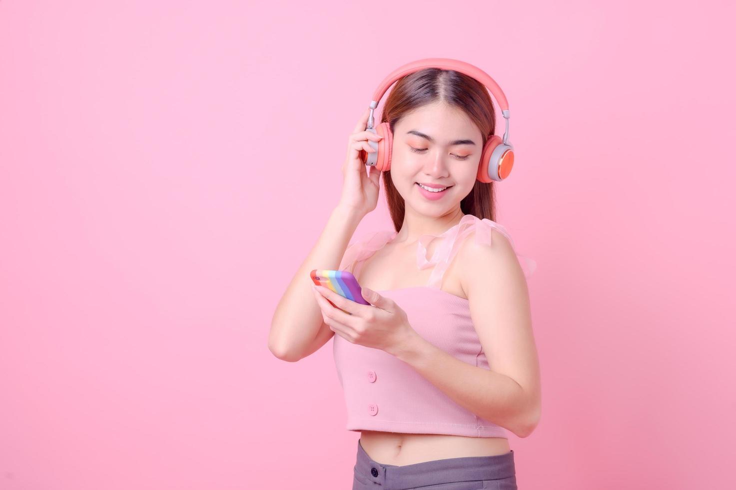 schöne asiatische mädchen hören online musik über ihre handy-internetverbindung und tanzen fröhlich foto