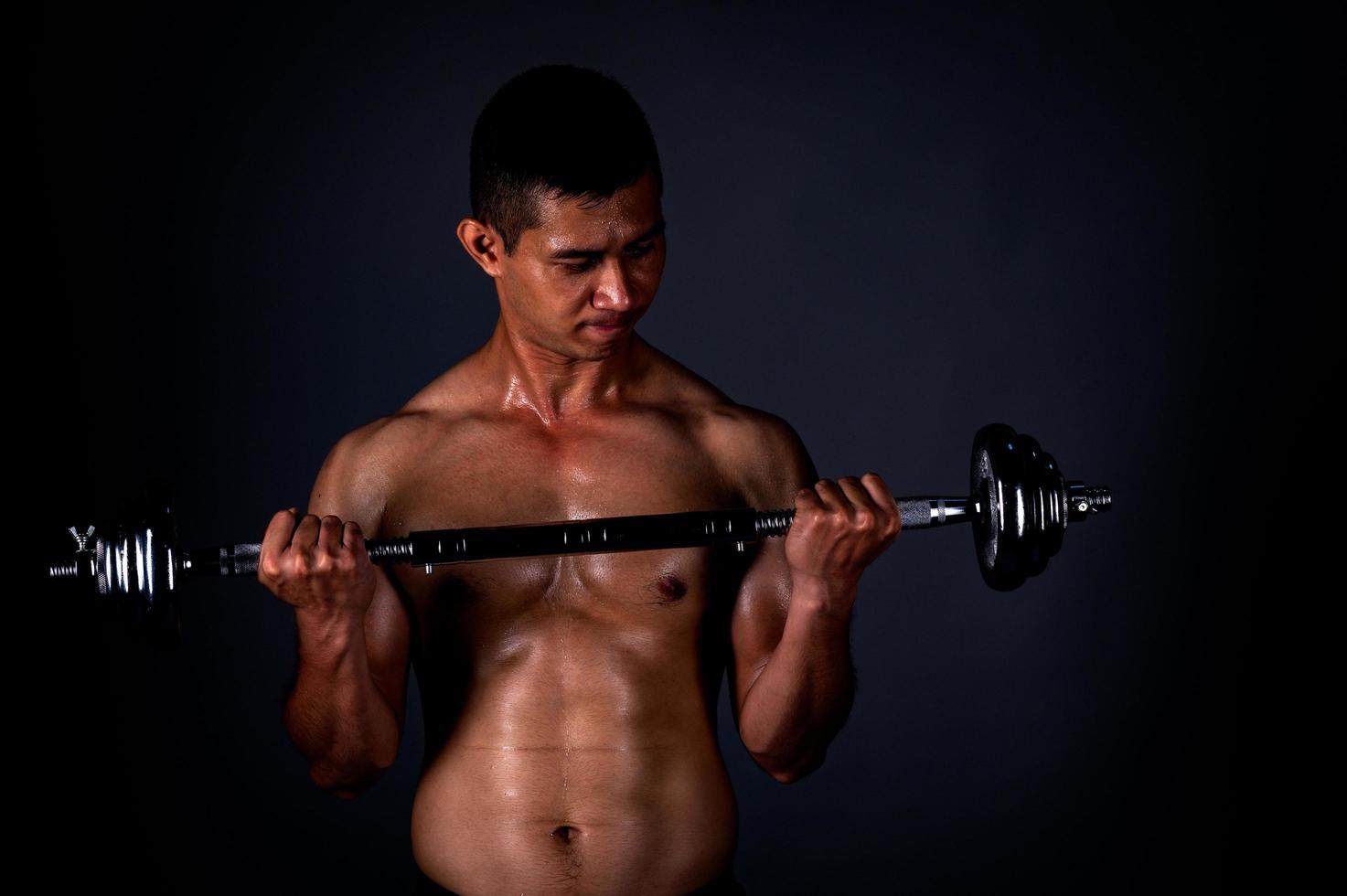 Der starke Asiate hob regelmäßig seine Hantel, um seine Muskeln stark und schön zu halten foto