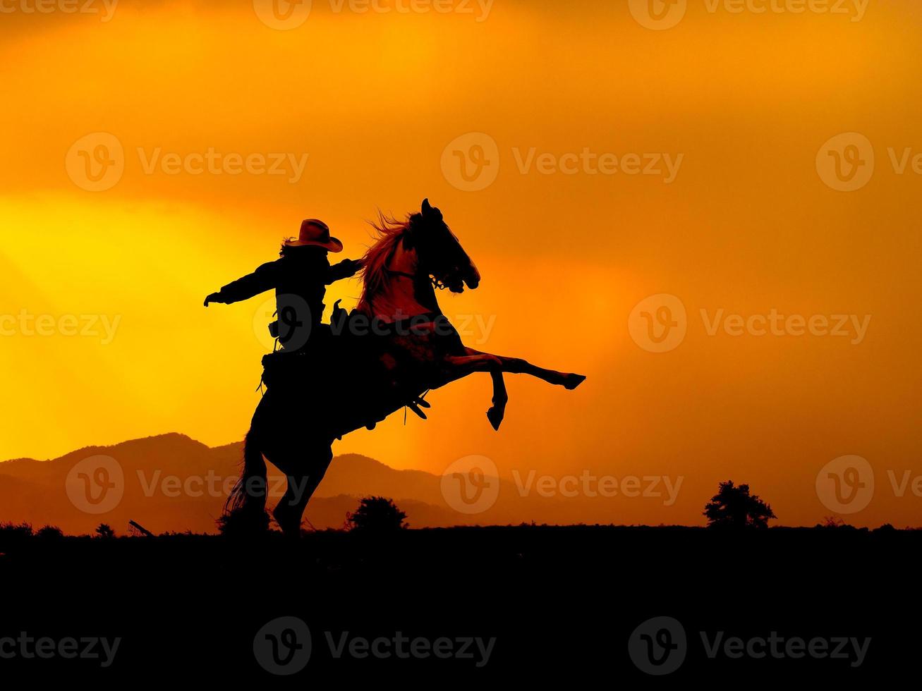 Western-Cowboys zwingen Pferde, sich hochzuheben, bereiten sich darauf vor, eine Waffe zu benutzen, um sich zu schützen foto