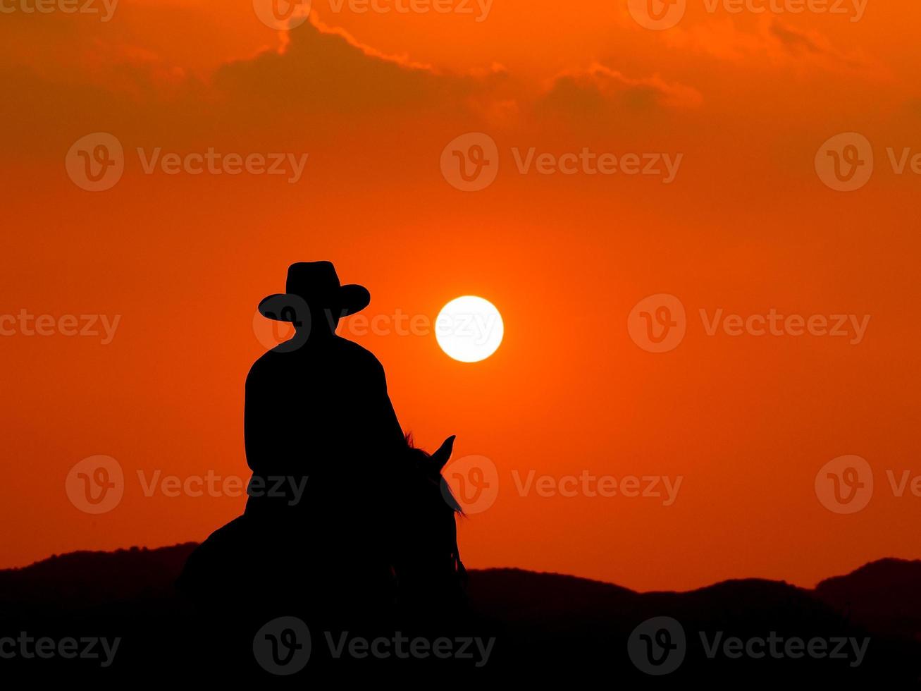 Der westliche Cowboy zwang seine Pferde, bei Sonnenuntergang anzuhalten, in Ländern, in denen das Gesetz noch nicht angekommen ist foto