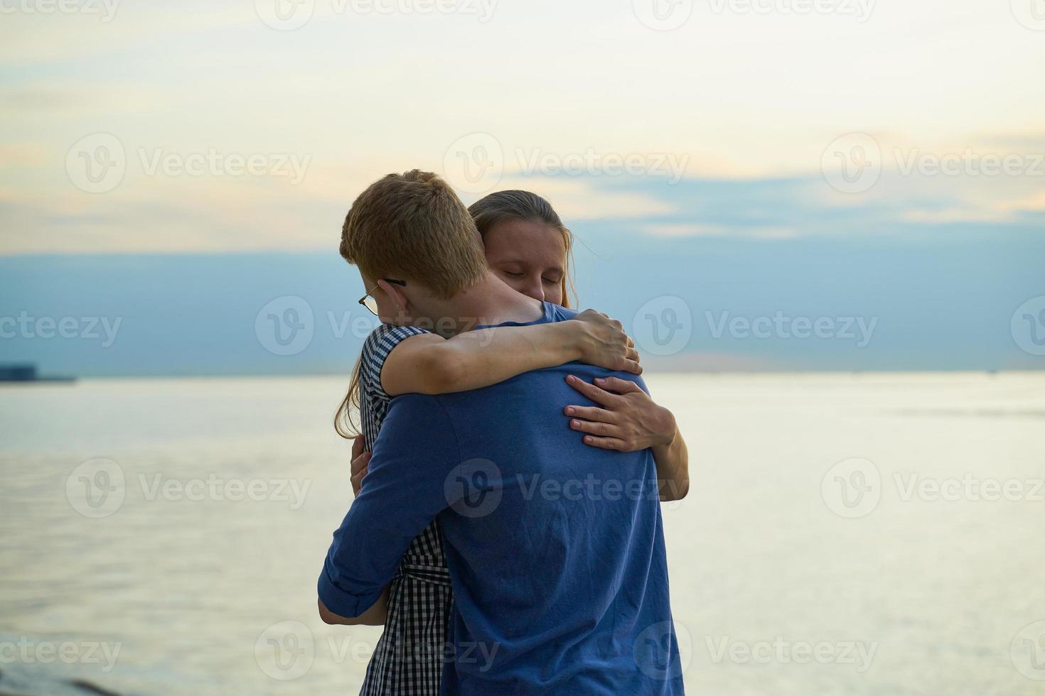 Mädchen umarmt Jungen am Strand, jugendlich Liebe bei Sonnenuntergang, Kopierraum foto