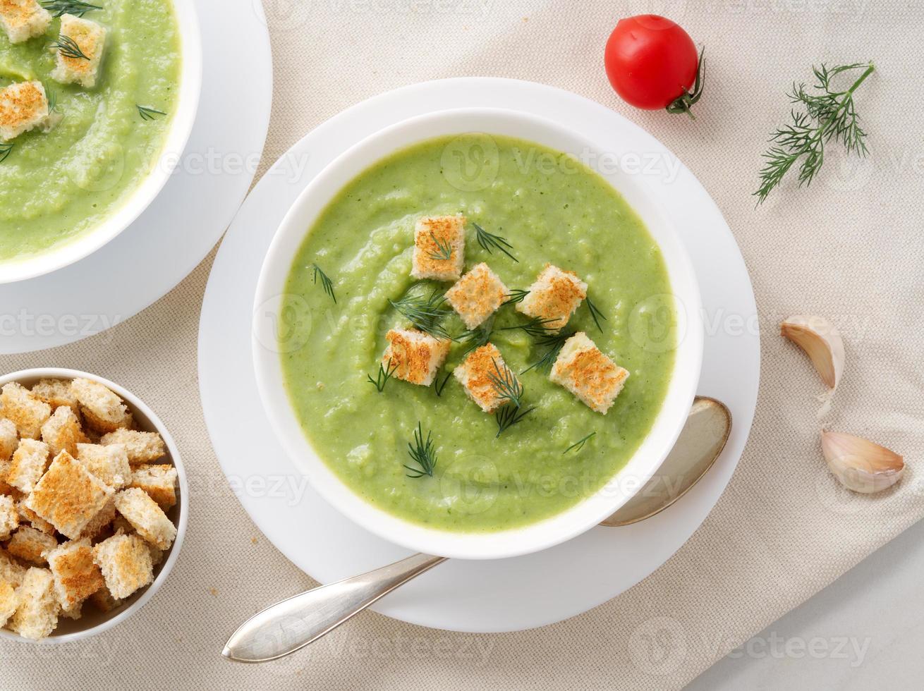 zwei große weiße schüssel mit gemüsegrüner cremesuppe aus brokkoli, zucchini, grünen erbsen foto