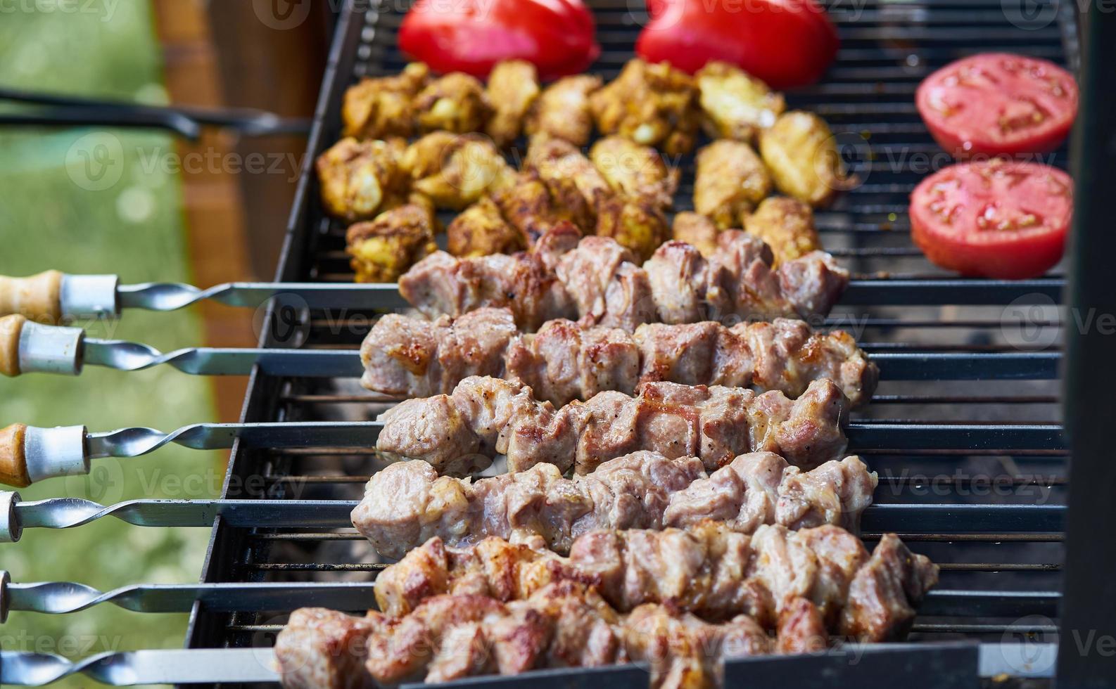 Barbecue-Schaschlik-Kebab mit Winglets und Tomaten mit gerösteter Paprika im Holzkohlegrill halbfertig foto